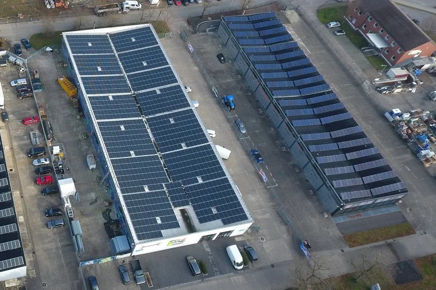 Solaranlage auf Dächern mit geparkten Autos. Das Bild zeigt eine große Solaranlage auf den Dächern von Gebäuden, die auf einem Gelände mit geparkten Autos installiert ist.