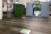 Kundencenter Theke mit Plexiglas und Abstandsinfo auf Fußboden im Service-Center