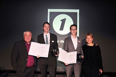 zwei Prüflinge mit Urkunden und Ausbildern