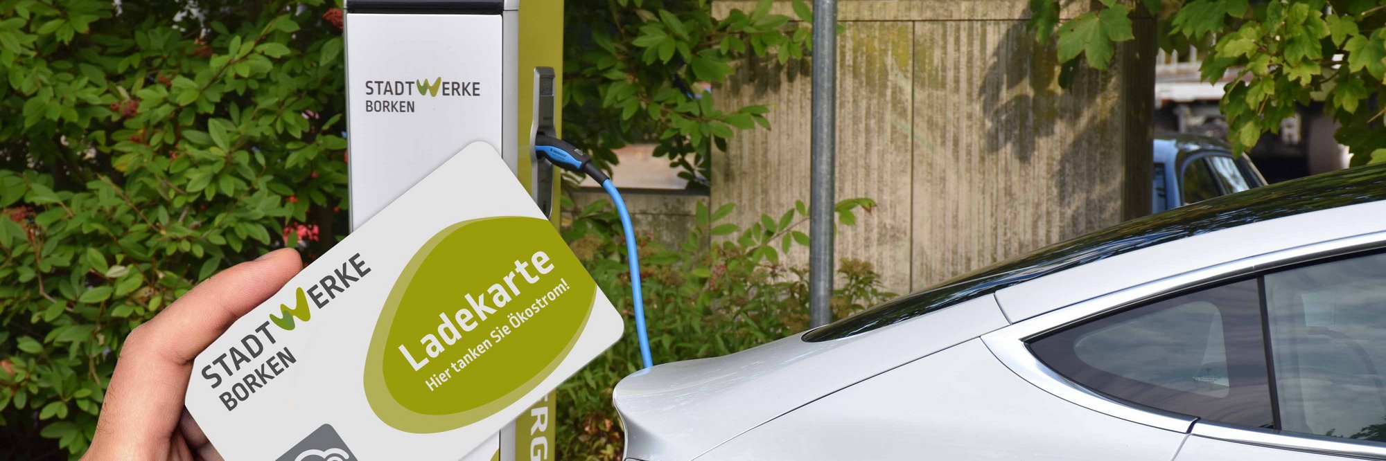 Person hält Ladekarte vor Elektroauto. Jemand hält eine Ladekarte in der Hand, während er sich einem Elektroauto nähert.