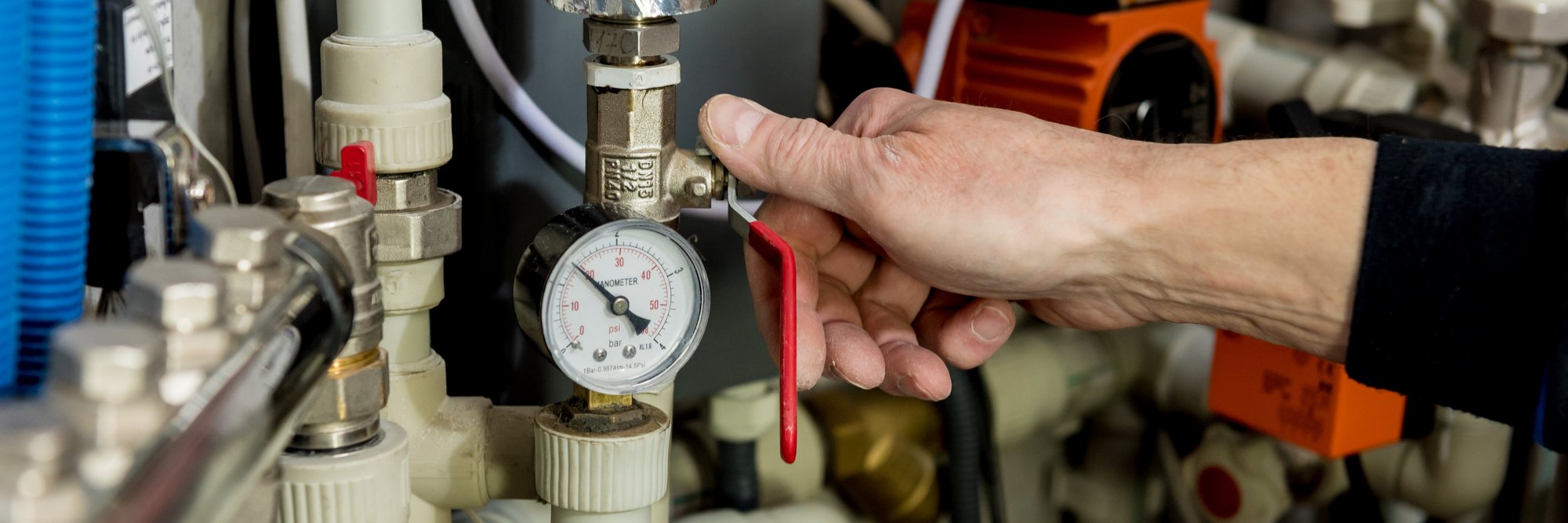 Person überprüft Manometer an Rohrleitung Person überprüft einen Manometer an einem Rohrleitungssystem.
