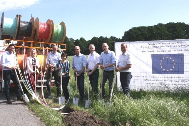 Glasfaser Velen Netzausbau Aussenbereich Velen sieben Vertreter der beteiligten Parteien vor Leerrohrwagen
