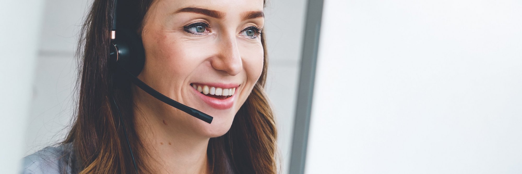 Lächelnde Person mit Headset im Gespräch Person mit einem Headset, die lächelt und wahrscheinlich in einem Kundendienstgespräch ist.