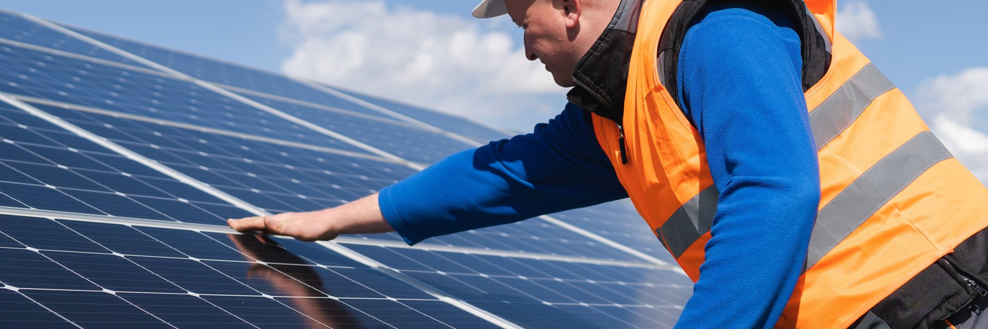 Arbeiter installiert Solarpanel in Schutzkleidung. Das Bild zeigt einen Arbeiter in Schutzkleidung und Helm, der ein Solarpanel installiert oder wartet.