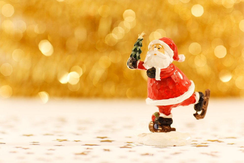 Das Bild zeigt eine kleine, festliche Weihnachtsmann, die auf dem Eis tanzt. 