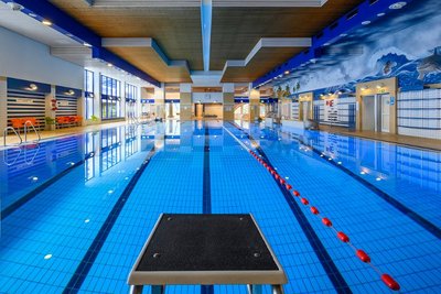Das Bild zeigt ein modernes Hallenbad mit einem klaren, tiefen Schwimmbecken. 