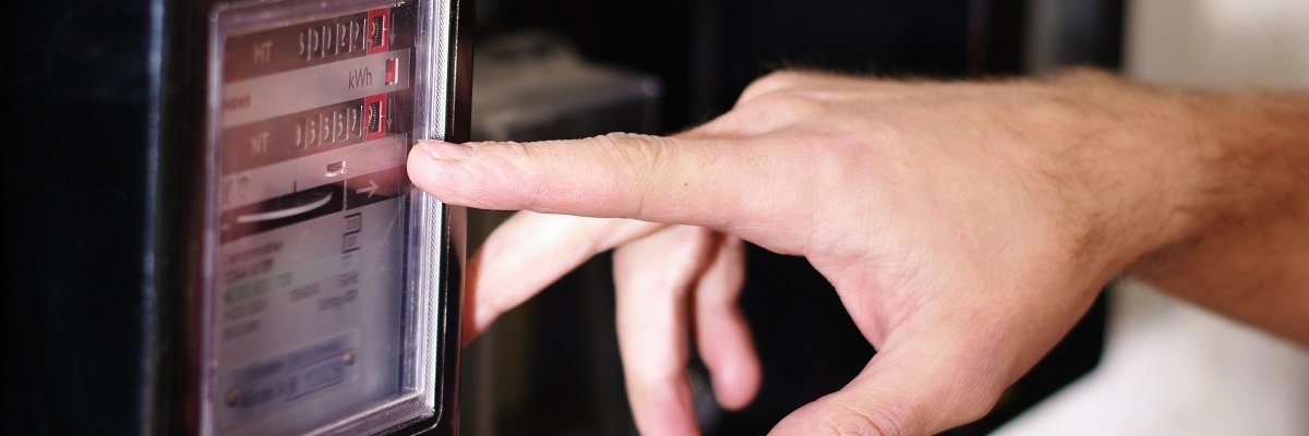 Messgerät wird von Hand abgelesen Hand, die auf einen Zähler oder Messgerät drückt, vermutlich zur Ablesung von Verbrauchsdaten.