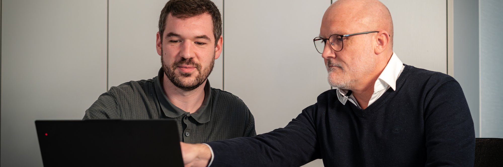 Zwei Personen schauen auf einen Laptop