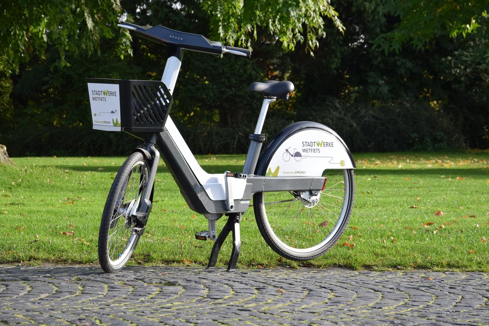 Fahrrad aus öffentlichem Verleihsystem im Park. ein Fahrrad aus einem öffentlichen Verleihsystem, mit einem "Stadtwerke"-Logo.