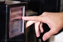 Einer Person zeigt mit dem Finger auf einen Stromzähler.
