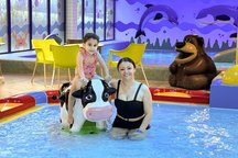 Das Bild zeigt eine Mutter und ihre Tochter, die zusammen in einem Kinderbecken in einem Schwimmbad stehen. 