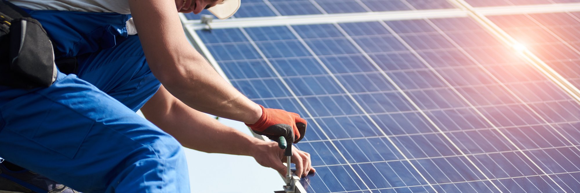 Person installiert Solarpanel auf dem Dach Das Bild zeigt eine Person, die auf einem Dach ein Solarpanel installiert.
