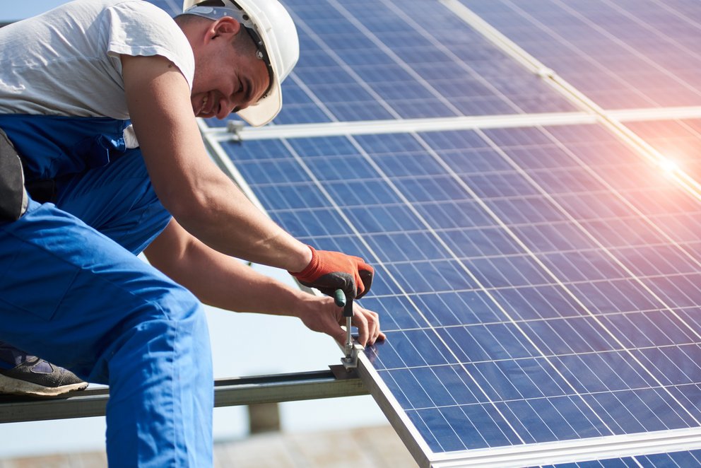 Arbeiter installiert Solarpanel auf Dach. Das Bild zeigt einen Arbeiter, der ein Solarpanel auf einem Dach installiert.
