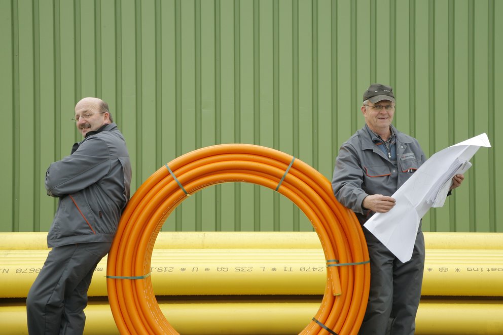 Arbeiter vor gelben Rohren Zwei Arbeiter vor gelben Rohren
