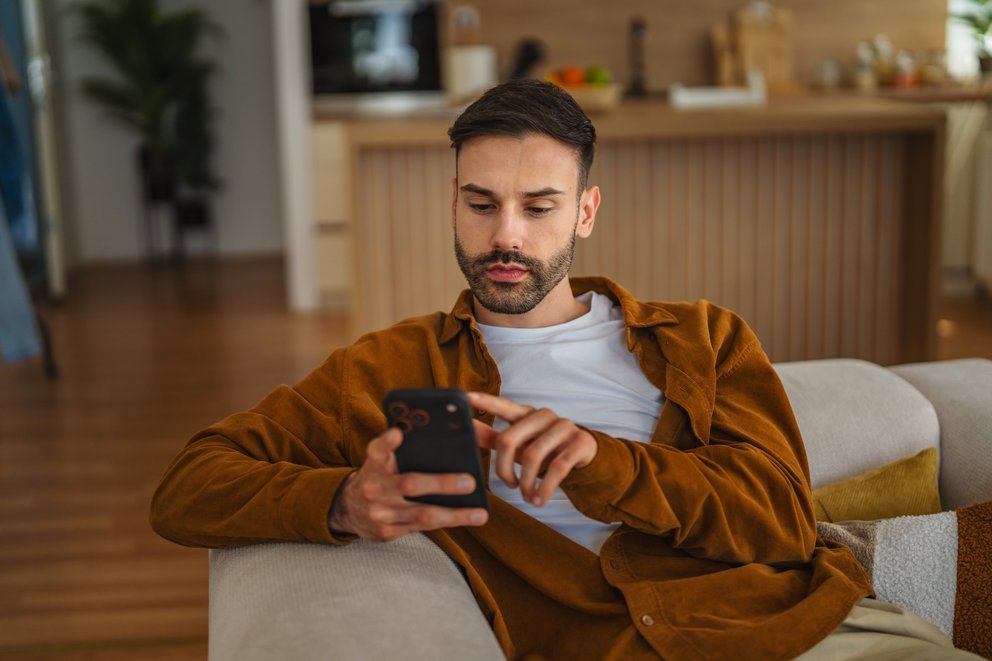 Mann mit Handy in der Hand Ein Mann schaut nachdenkend auf sein Handy
