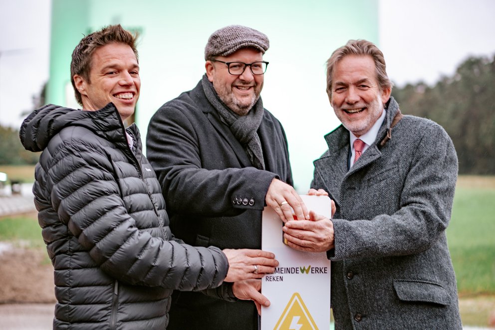 Gemeinde Werke Reken Drei Männer mit EMERGY-Schild im Freien