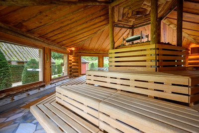 Das Bild zeigt das Innere einer Sauna mit großzügig angeordneten Bänken aus Holz.