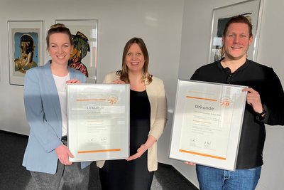 Die Mitarbeiter präsentieren die neuen Urkunden des Top-Lokalversorger Siegels.