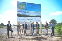 Team vor Banner eines Windkraftprojekts eine Gruppe von Personen, die ein Baustellenbanner für ein Windkraftprojekt präsentieren.