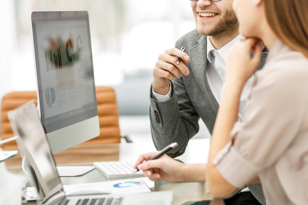 Zwei Personen sitzen am Computer und sprechen miteinander. Zwei Personen sitzen am Computer und sprechen miteinander.